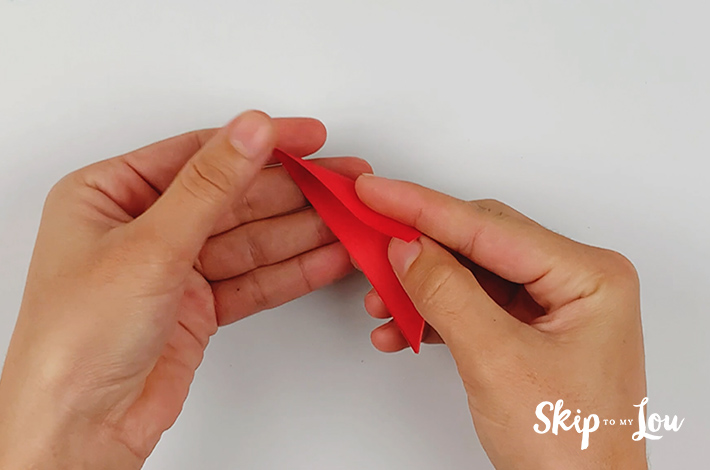 Two hands making the first origami folds for a paper petal.
