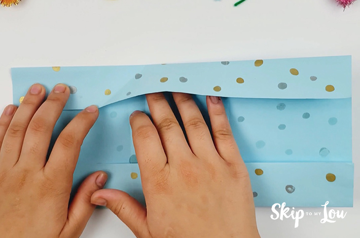 Two hands placed under the top flap to make a 45-angle fold.