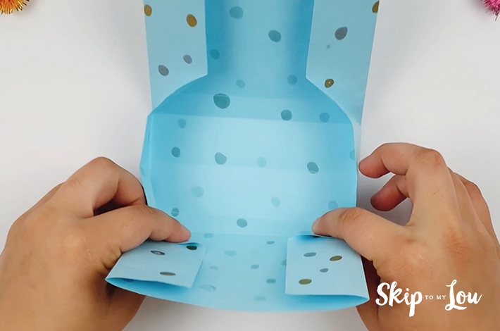Two hands folding the paper in exactly the same way on the left hand side.