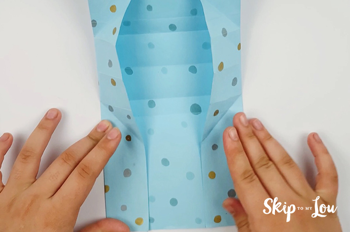 Two hands securing the paper in the sections where the glue was applied.