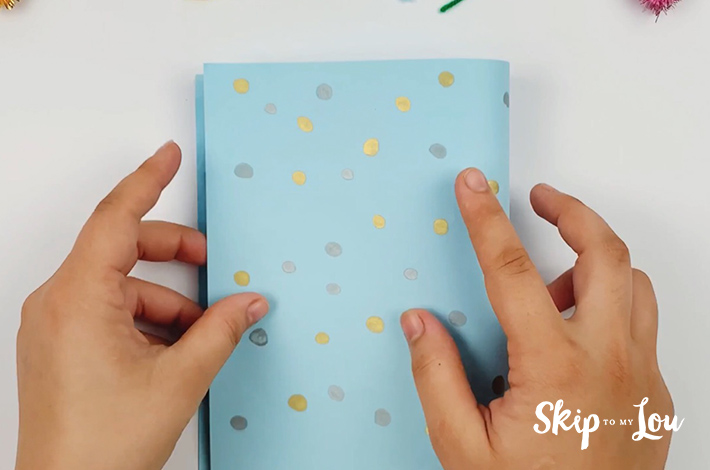 Two hands folding the paper in half.
