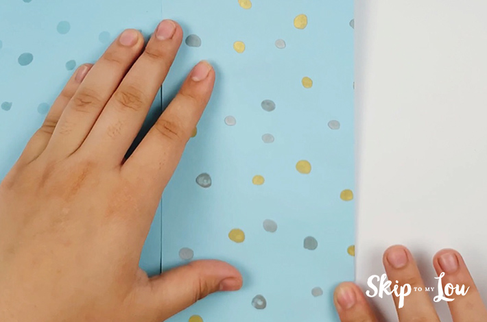 Two hands folding from the right-hand side, in line with the furthest fold from the left.