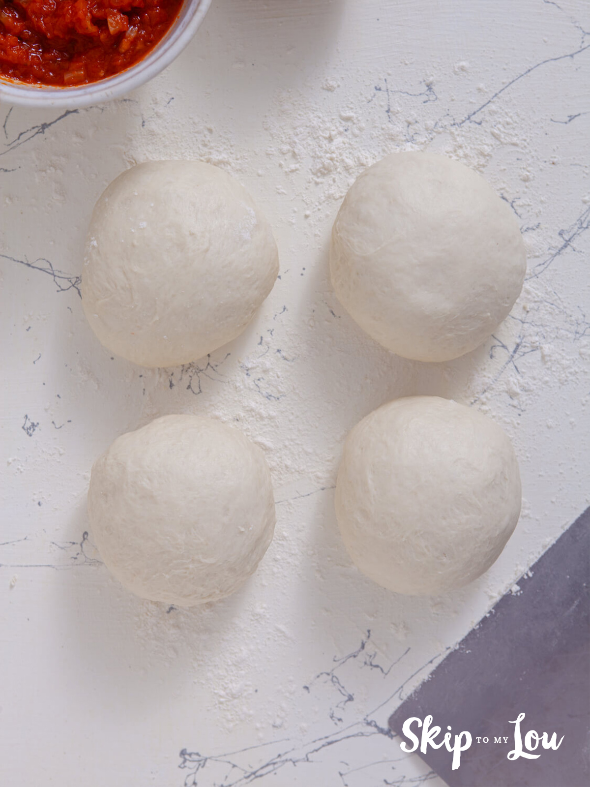 Four pizza dough balls ready to be rolled out.