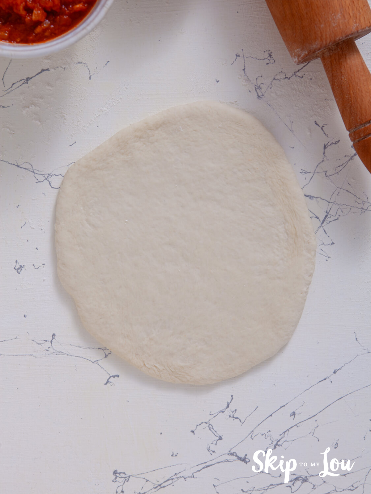 A pizza dough ball rolled out.