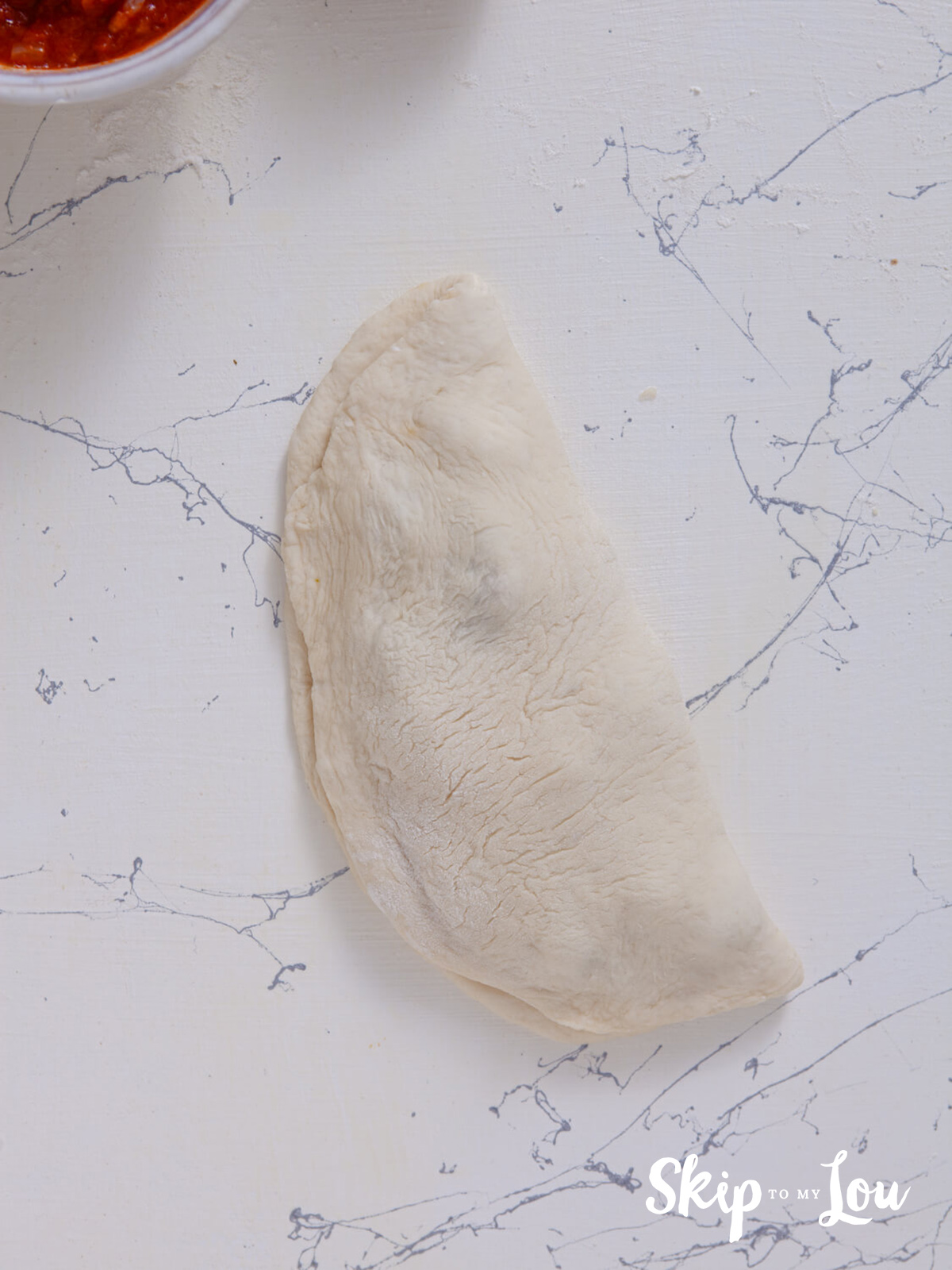 The other half of the pizza round is folded over the filling and the edges are crimped.