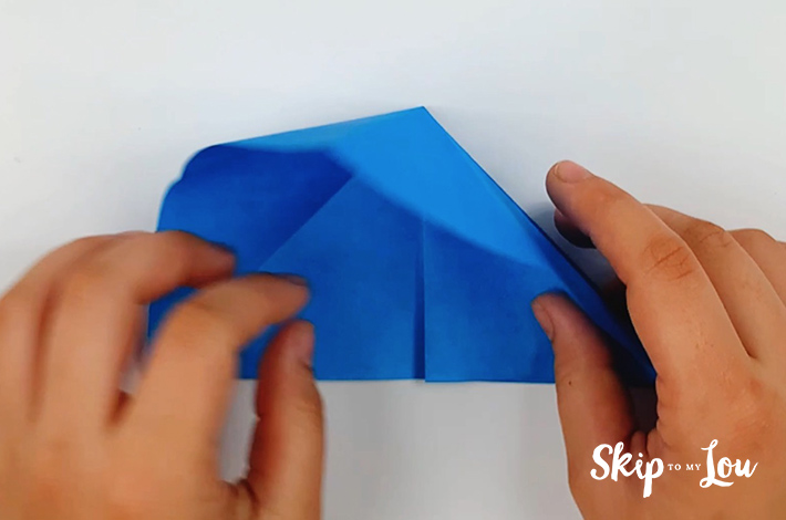 Two hands folding the paper inwards.