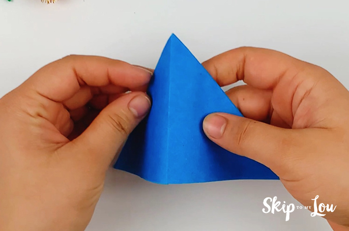 Two hands folding the triangle in half again.