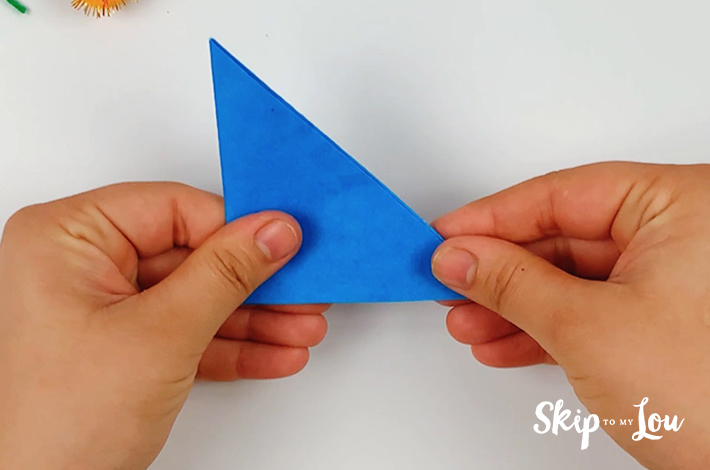 Two hands holding the smaller folded triangle.