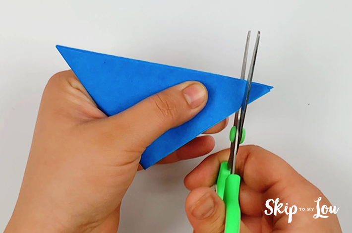 Two hands cutting the right flap with a pair of scissors. 