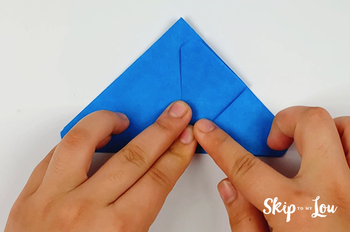 Two hands folding the right flap upwards.