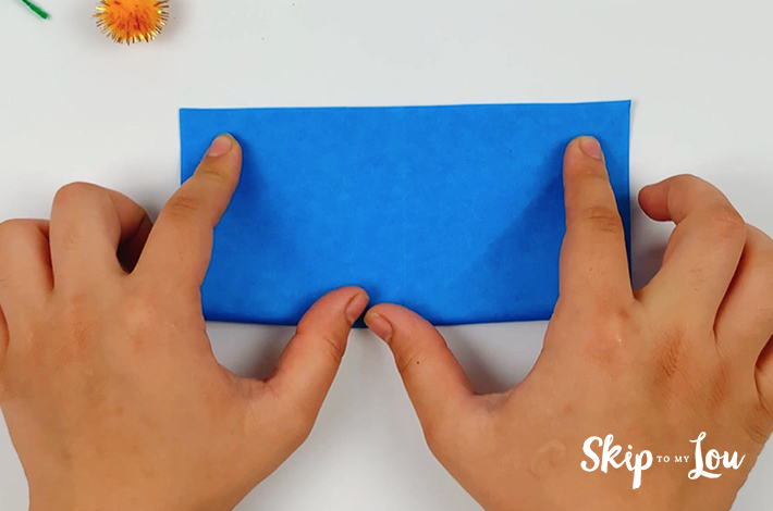 Two hands folding the paper in half again.