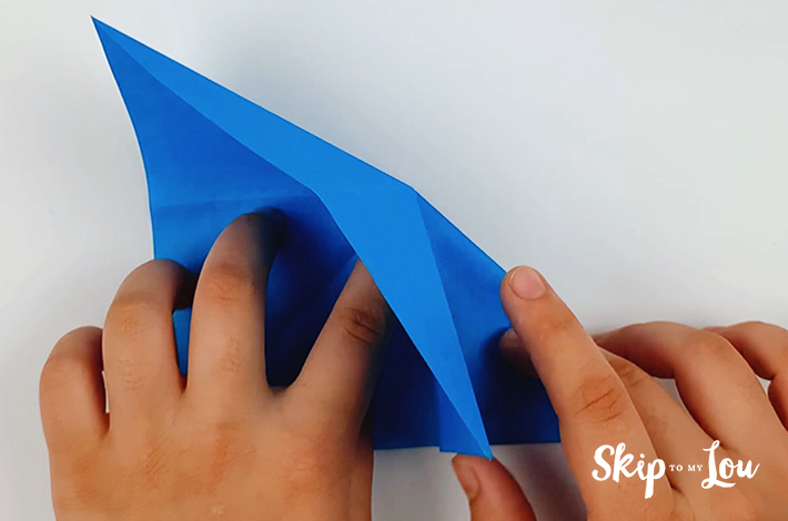 Two hands folding the paper inwards.