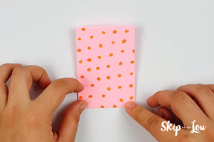 Two hands securing the fold to form a square.