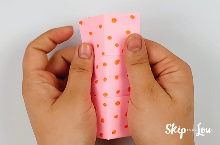 Two hands folding the paper in half along the center line.