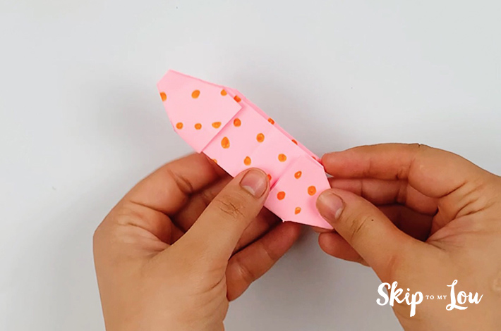 Two hands holding the paper once it has been cut.