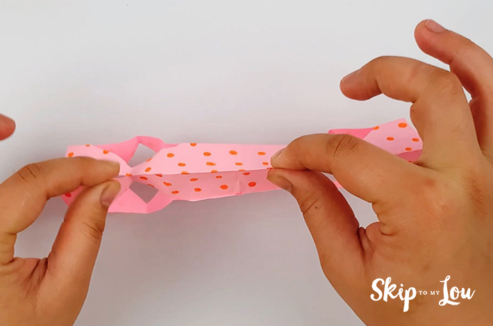 Two hands ensuring all the creases are tightly folded to enhance the box shape.