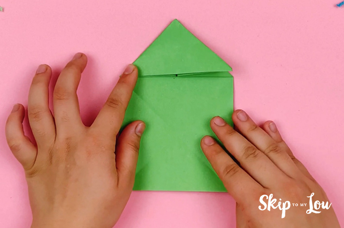 Two hands pushing the top triangle flat. 