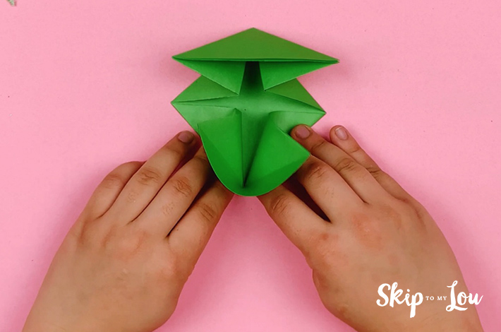 Two hands folding the bottome section into a triangle. 