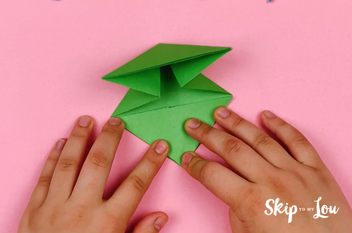 Two hands pushing the bottom triangle flat. 