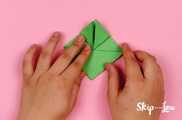 Two hands folding the top left flap upwards.