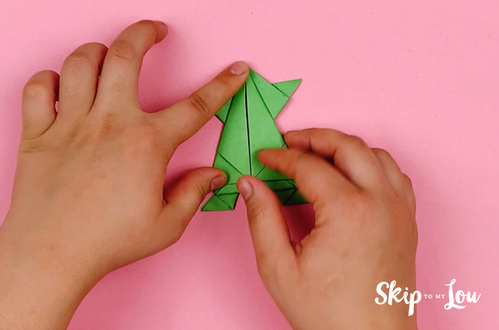 Two hands folding the left corner over to the center. 
