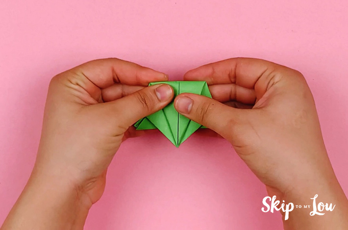 Two hands folding the paper along the center. 