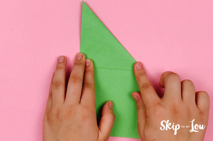 Two hands folding the top right corner along the visible crease line. 