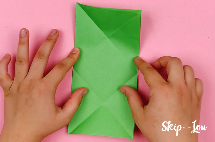 Two hands unfolding the paper into the rectangular shape again.