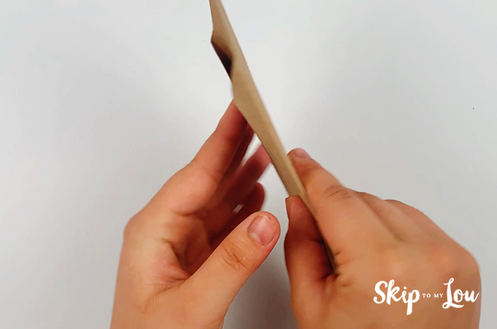 Two hands flipping the paper over 180 degrees.