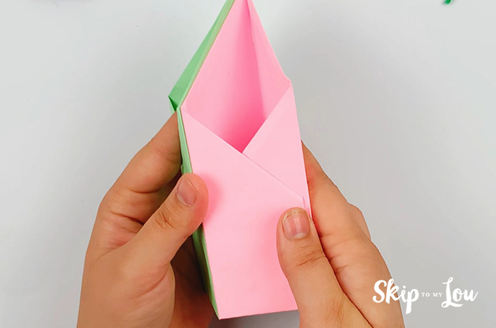 Two hands sticking two paper pen holders together after glue has been applied.