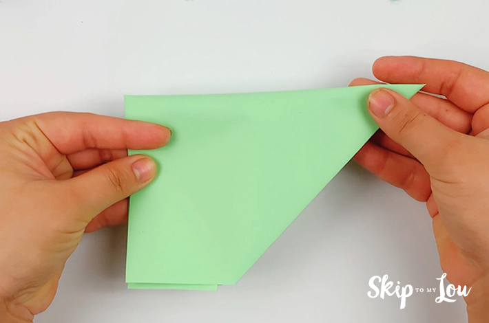 Two hands holding the paper which has been folded in half.