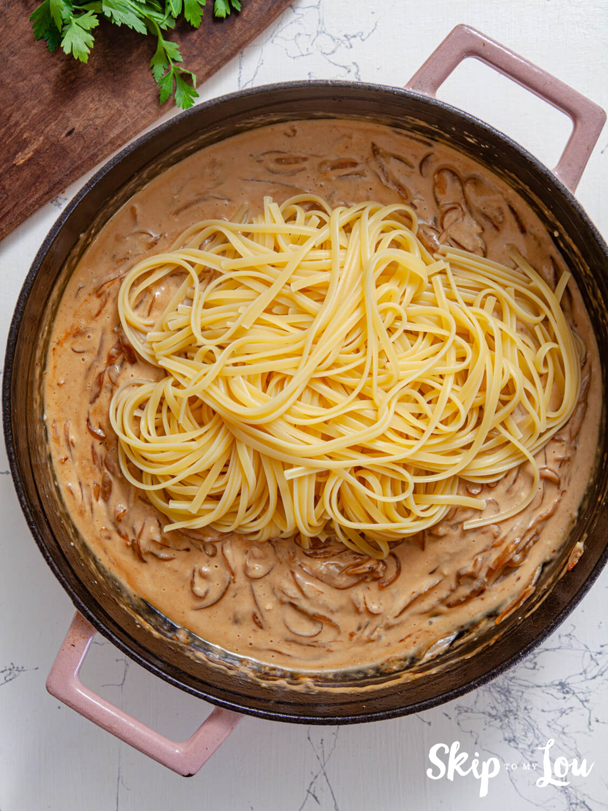 A skillet with caramelized onions with cream, parmesan and lemon and linguine added.