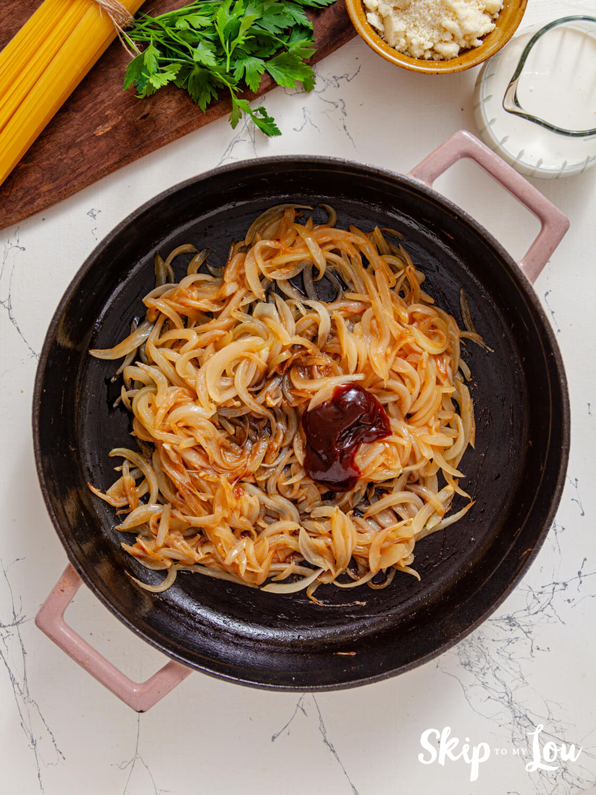 Onions frying in a skillet with balsamic vinegar and onions added.