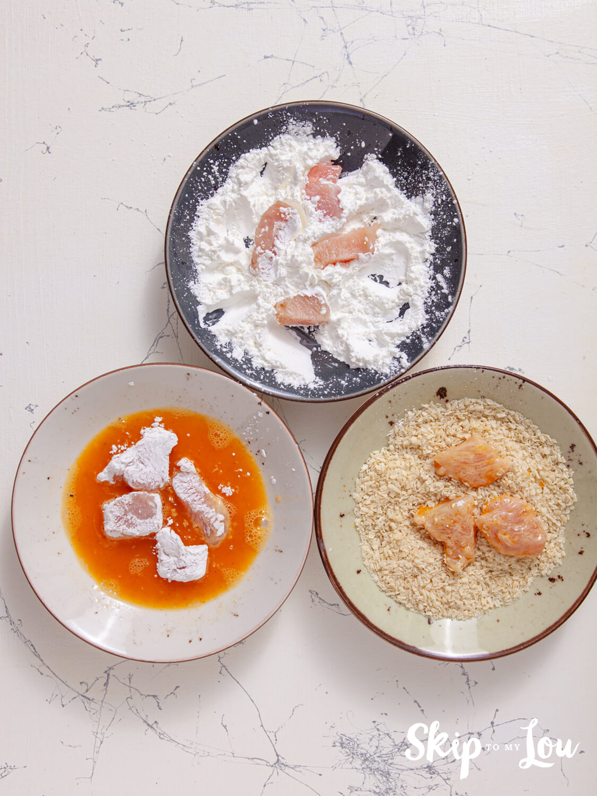 The chicken coating process from dredging it in corn flour, to egg and then coating with panko crumbs. 