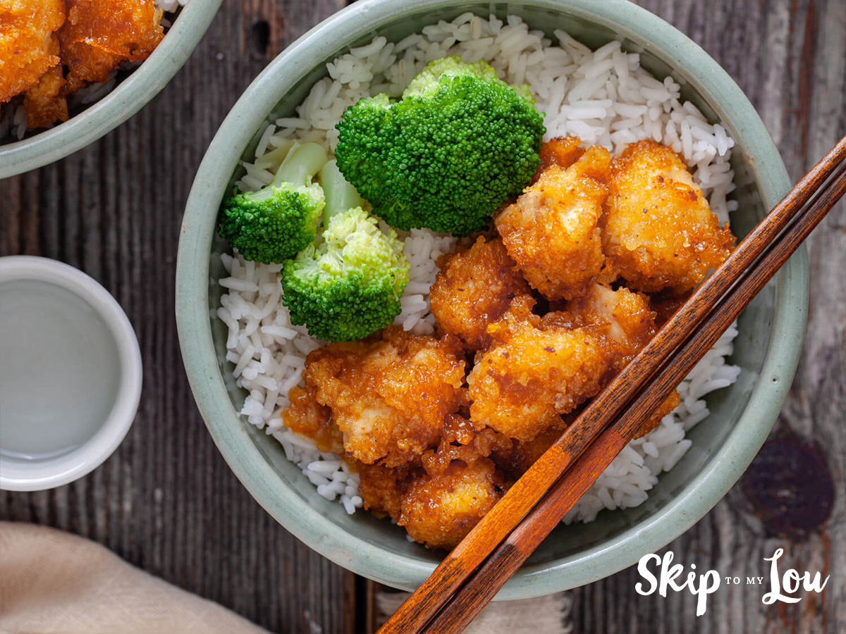 Easy baked organge chicken from Skip to My Lou served with rice and broccoli in a bowl.