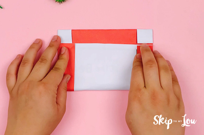 Two hands folding the bottom upwards in line with the first crease line. 