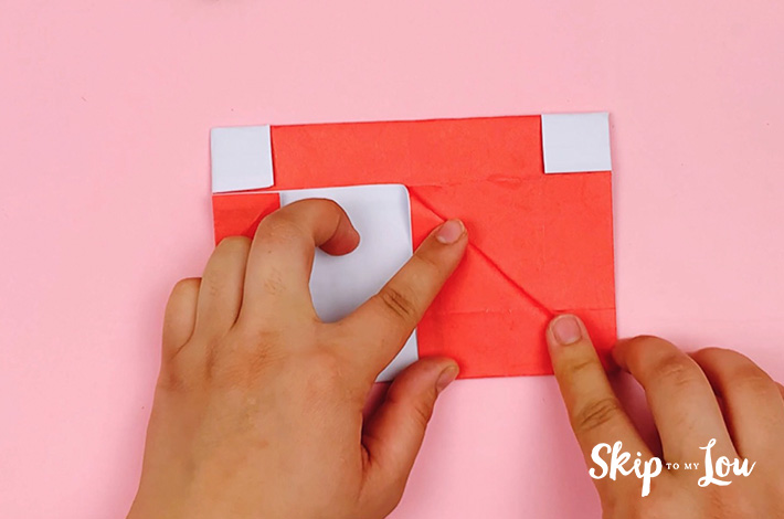 Two hands folding the right-hand side to form a triangle. 