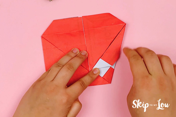 Two hands folding the right-hand side of the paper at a 45-degree angle after flipping it 180 degrees.