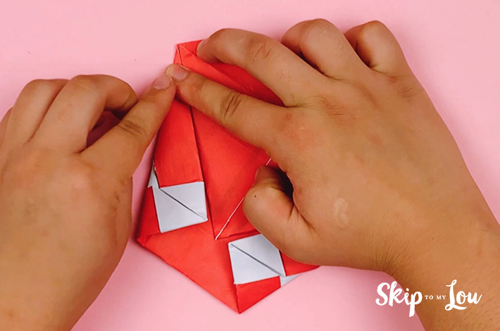Two hands folding the left-hand side of the paper at a 45-degree angle