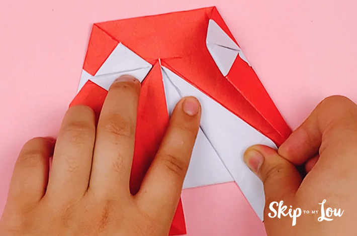 Two hands folding the central right flap of paper outwards. 