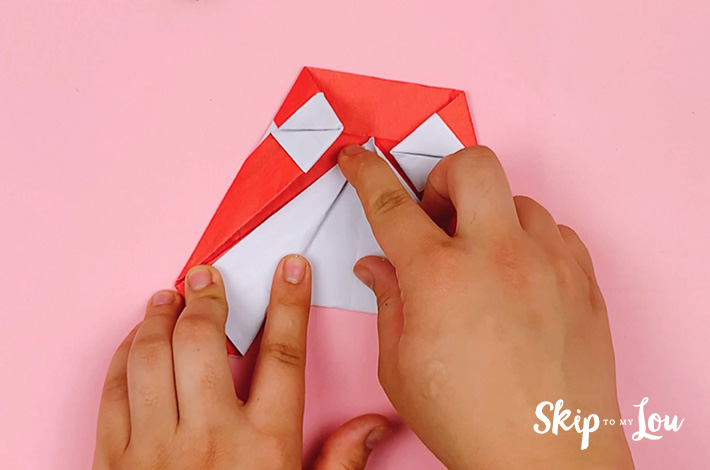 Two hands folding the central left flap of paper outwards. 
