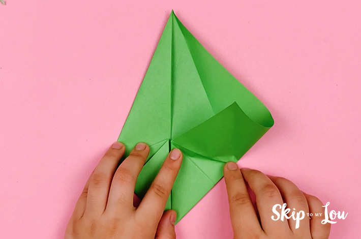 Two hands folding the bottom right side of the paper upwards.