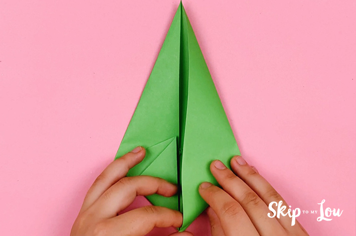 Two hands creasing the fold to form a kite shape on the right hand side.