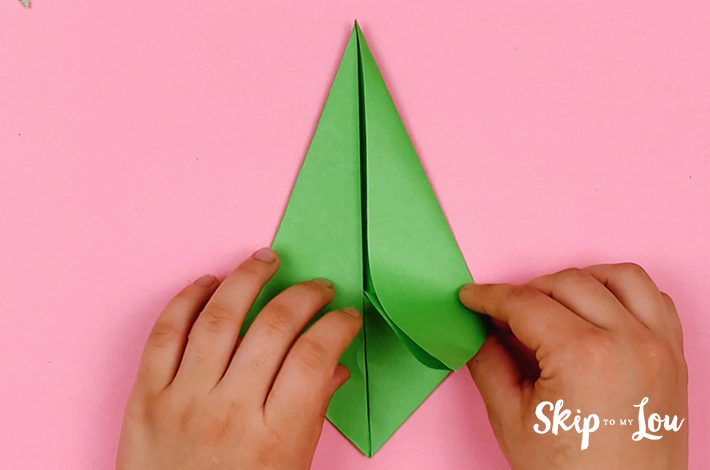 Two hands folding the bottom section of the paper.