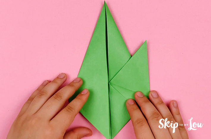 Two hands folding the bottom right section up and at an angle.