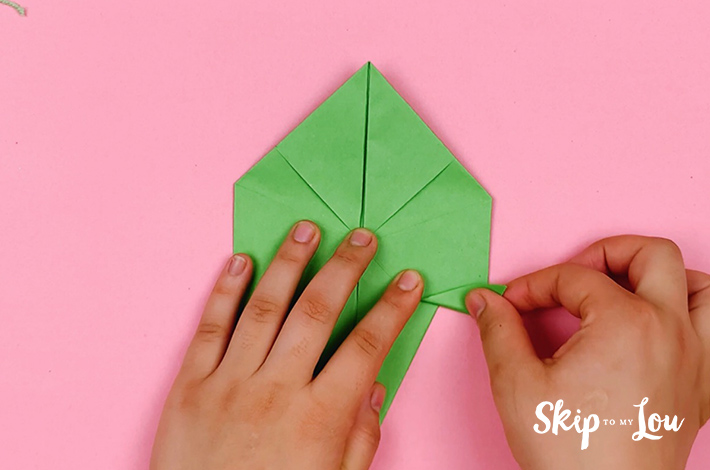 Two hands making a small fold on the right hand side after flipping the paper 180 degrees.
