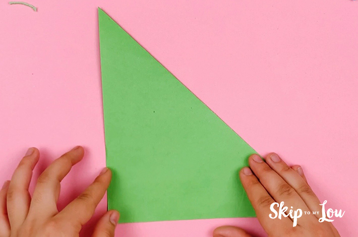 Two hands folding the paper at a 45 degree angle to form a triangle.