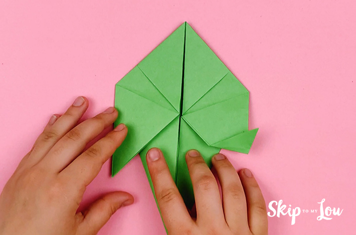 Two hands making a small fold on the left hand side after flipping the paper 180 degrees.