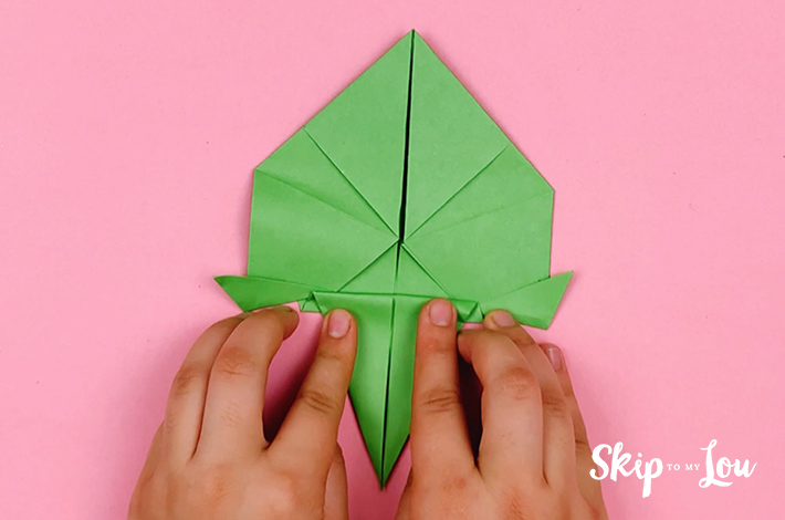Two hands then folding the top section of the bottom triangle that was just folded upwards back down, making a crease line.