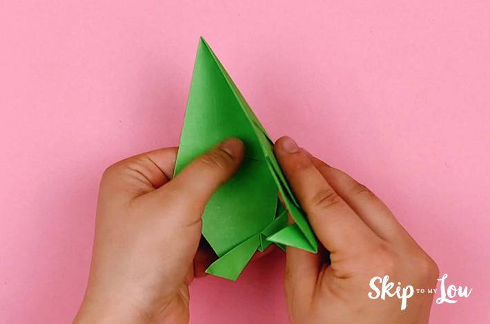 Two hands folding the paper in half along a center line.